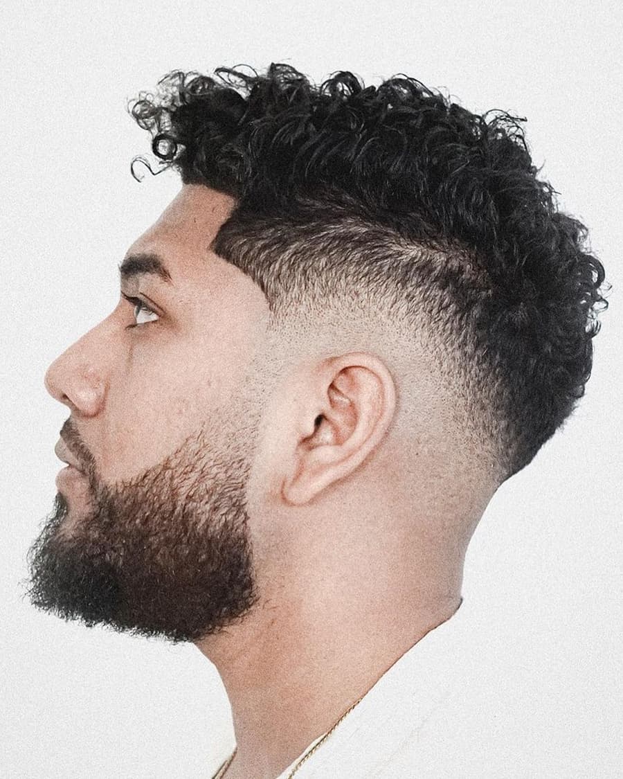 Man with curly hair and a high drop fade