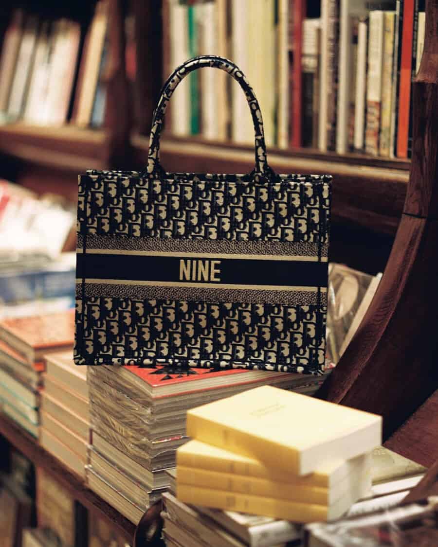 Luxury branded Dior tote bag on a pile of books