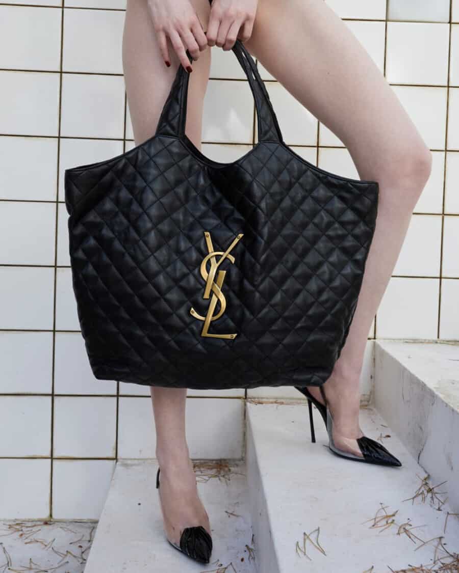 Woman holding a black quilted luxury Saint Laurent tote bag