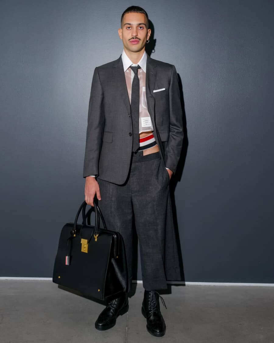 Man wearing short Thom Browne tailoring holding a luxury leather tote bag