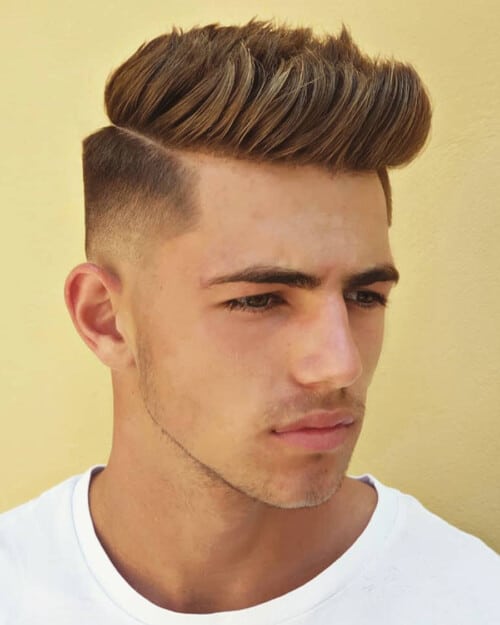 Man with thick hair wearing a pompadour with high fade