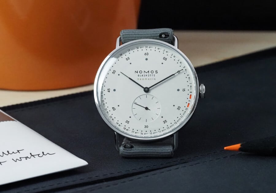 A Nomos minimalist watch resting on table