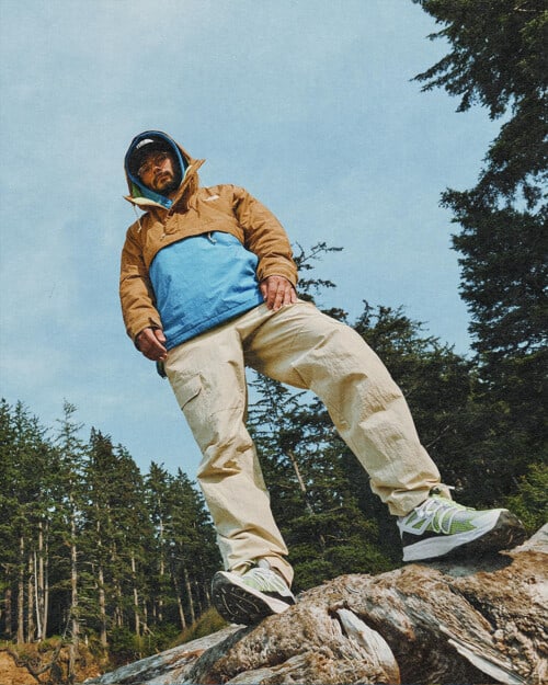 Man wearing North Face cargo pants, pullover jacket, baseball cap and trail runners outdoors