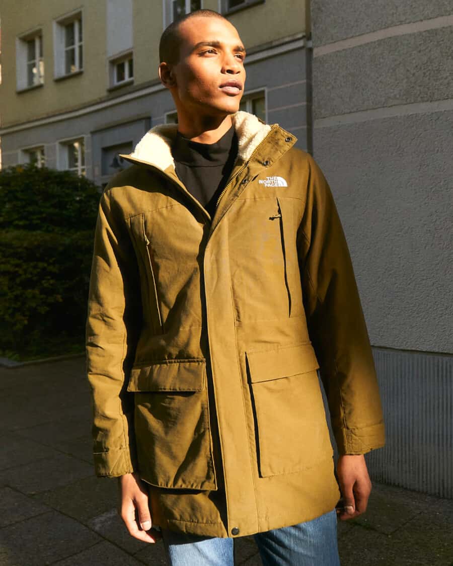 Man wearing a North Face long beige parka jacket with jeans