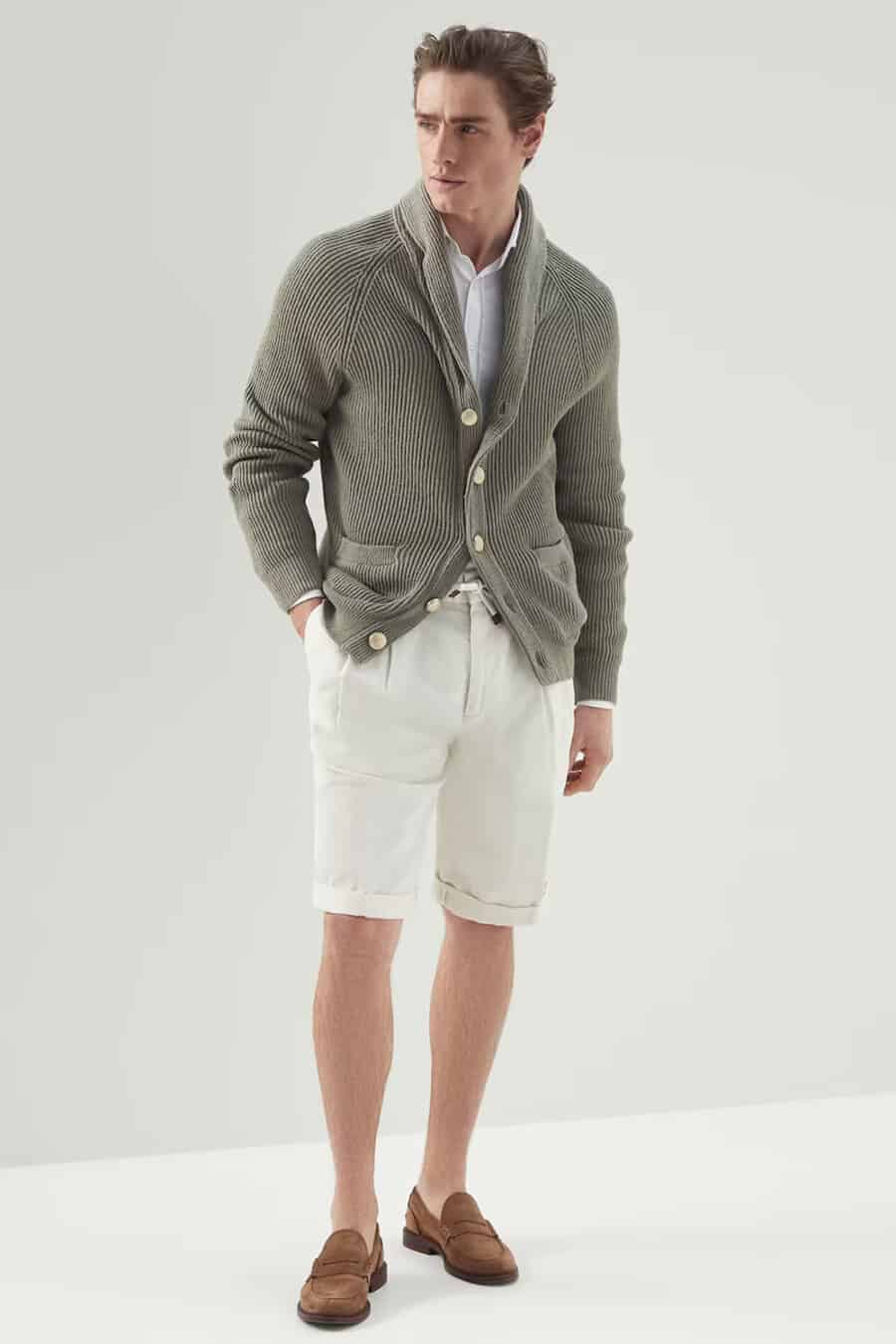 Men's off white pleated shorts, white shirt, green shawl collar cardigan and light brown suede penny loafers outfit