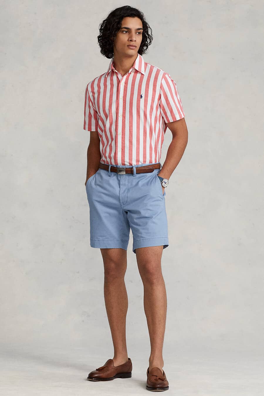 Men's pastel blue shorts, pink and white vertical striped shirt, brown leather belt and brown leather tassel loafers outfit
