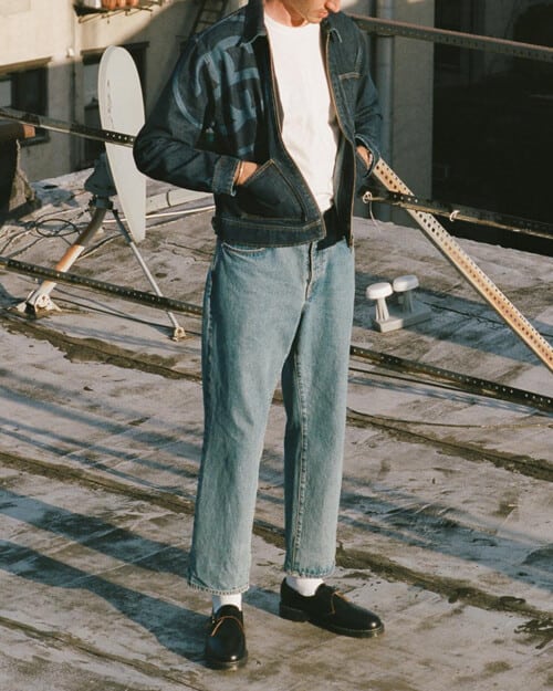 Man wearing loose fitting Stussy jeans with a white T-shirt and jacket