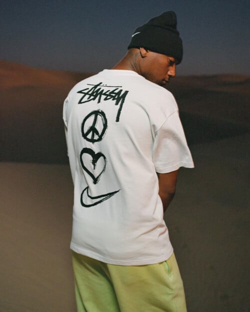 Man wearing Stussy white T-shirt with branding across the back