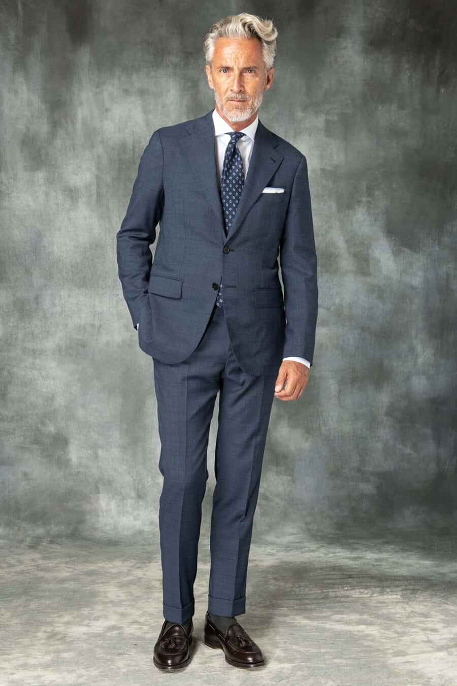 Men's blue lounge suit, white shirt, patterned navy tie, dark socks and dark brown leather tassel loafers outfit