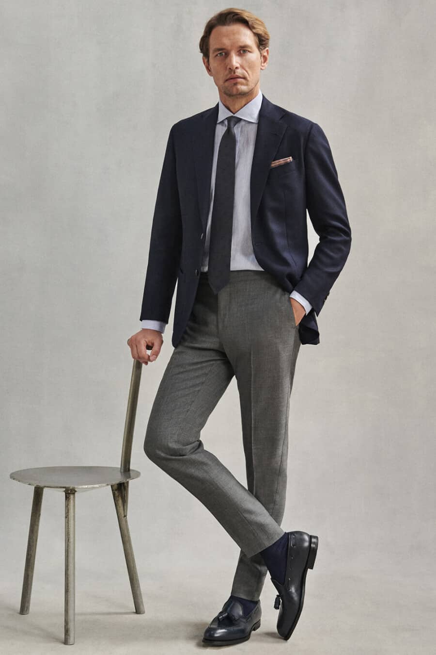 Men's grey trousers, navy blazer, light blue shirt, navy tie and navy leather tassel loafers outfit