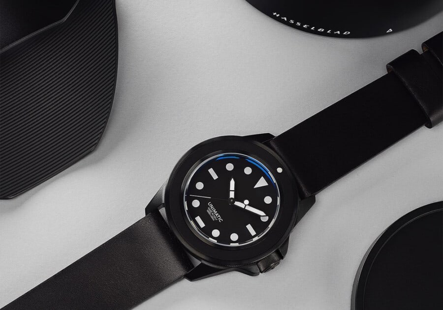 Minimalist black Unimatic watch laid out on grey table