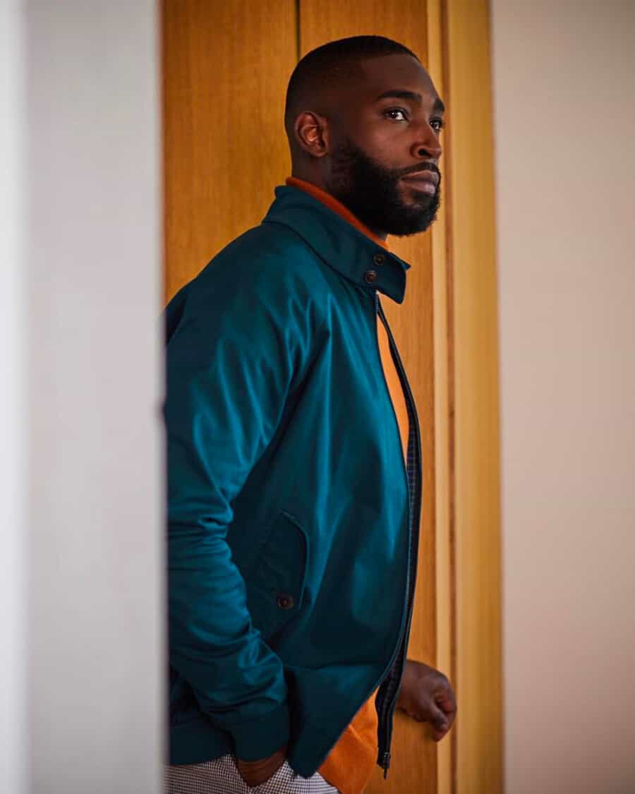 Black man wearing a marine blue-green Ben Sherman Harrington jacket