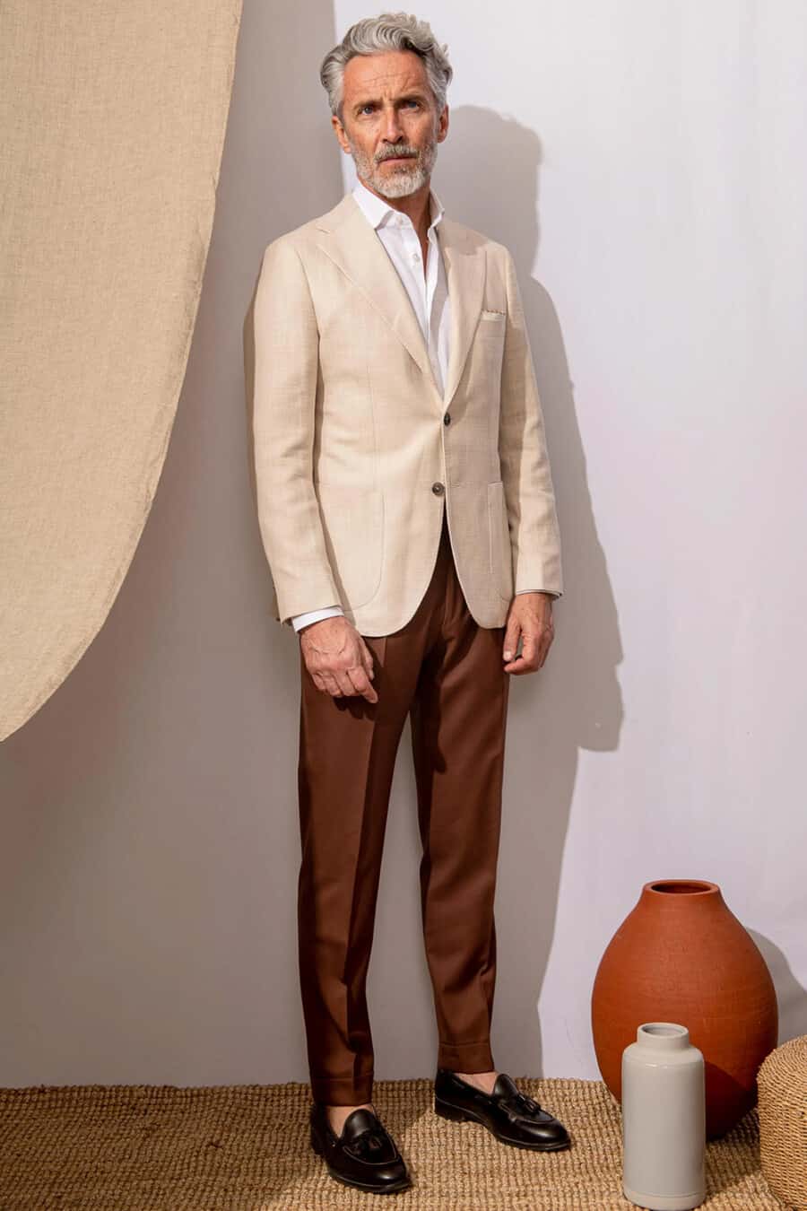 Men's rich brown trousers, white dress shirt, cream blazer and brown leather tassel loafers outfit