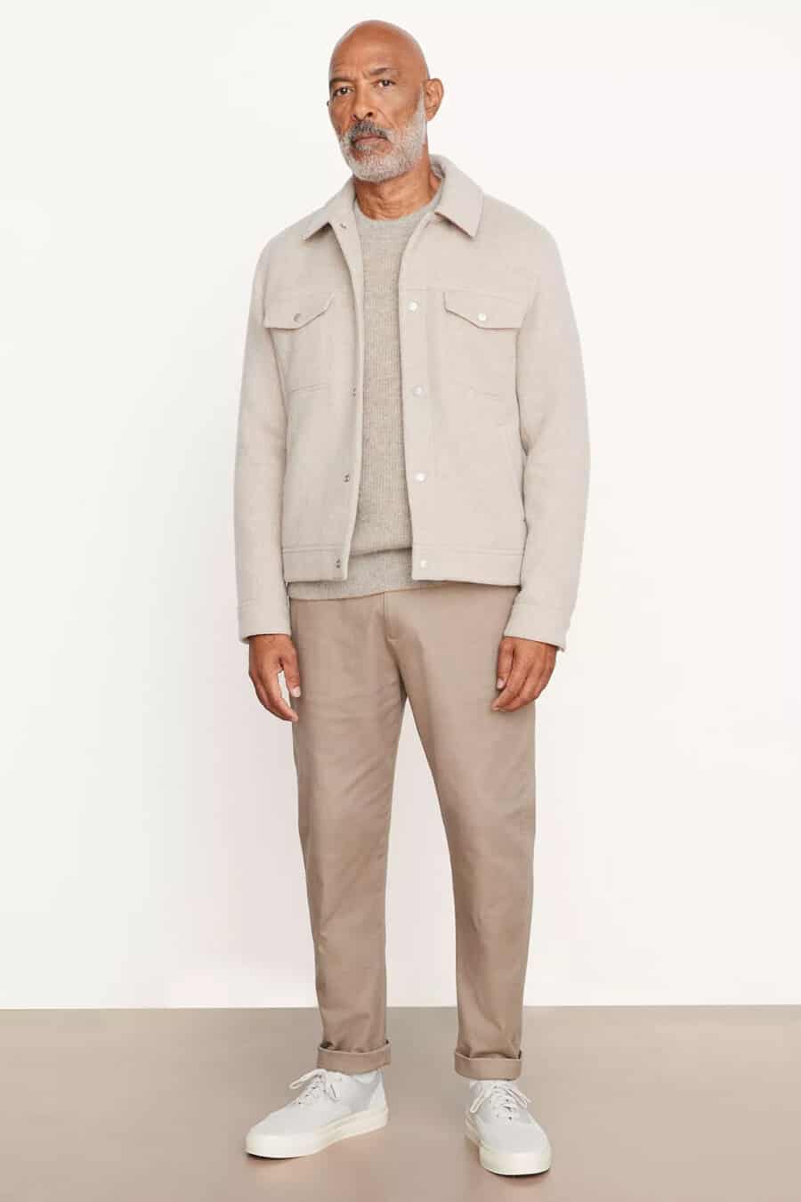 Men's light brown pants, stone sweater, ecru wool overshirt and white canvas sneakers outfit