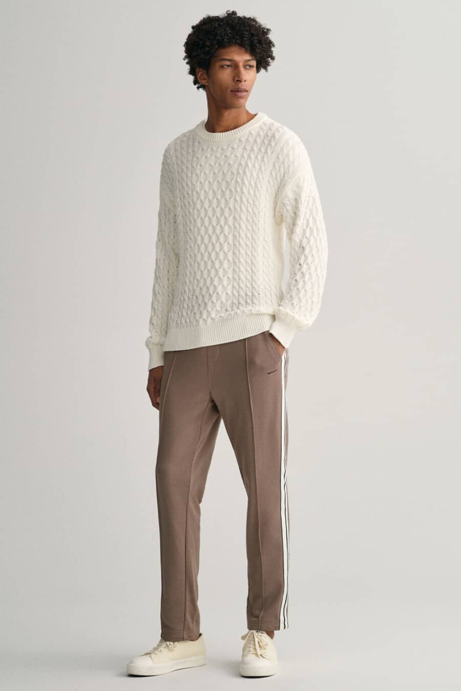 Men's brown trackpants, white cable knit sweater and off-white canvas sneakers outfit