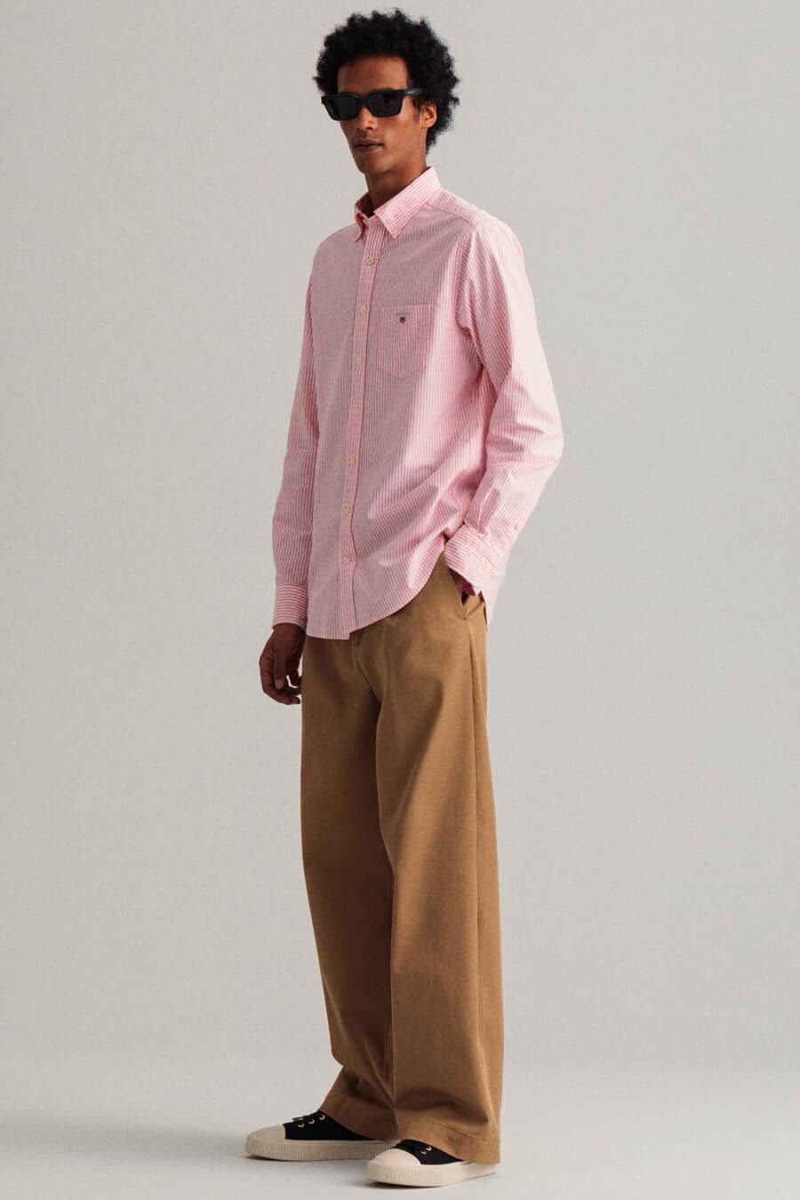Men's loose brown pants, light pink shirt and canvas sneakers outfit