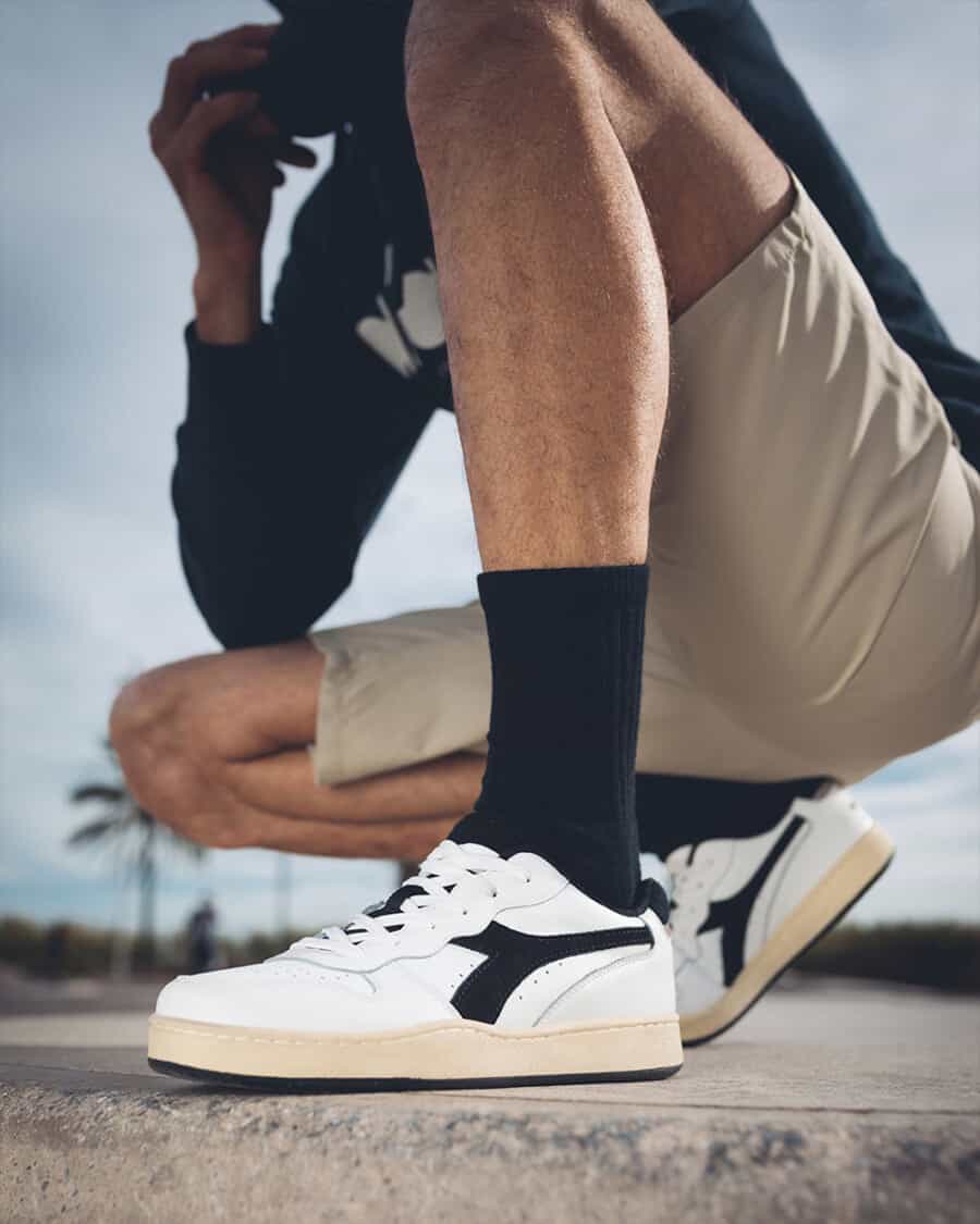 Classic affordable Diadora sneakers worn on feet with beige shorts and black sports socks