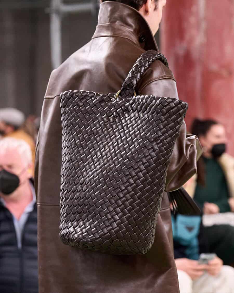 Man holding a luxury brown intrecciato leather tote bag by Bottega Veneta