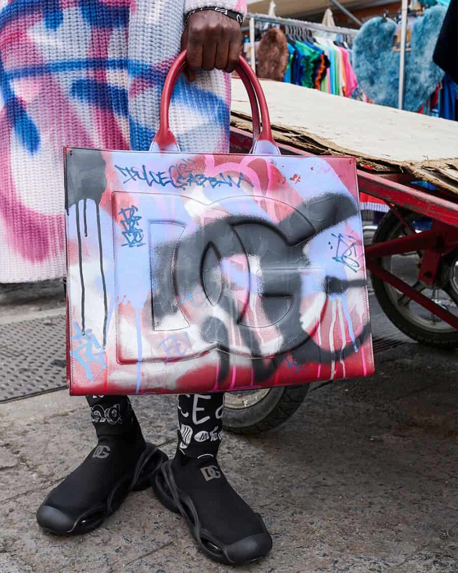 Man holding a luxury graffiti tote bag by Dolce & Gabbana