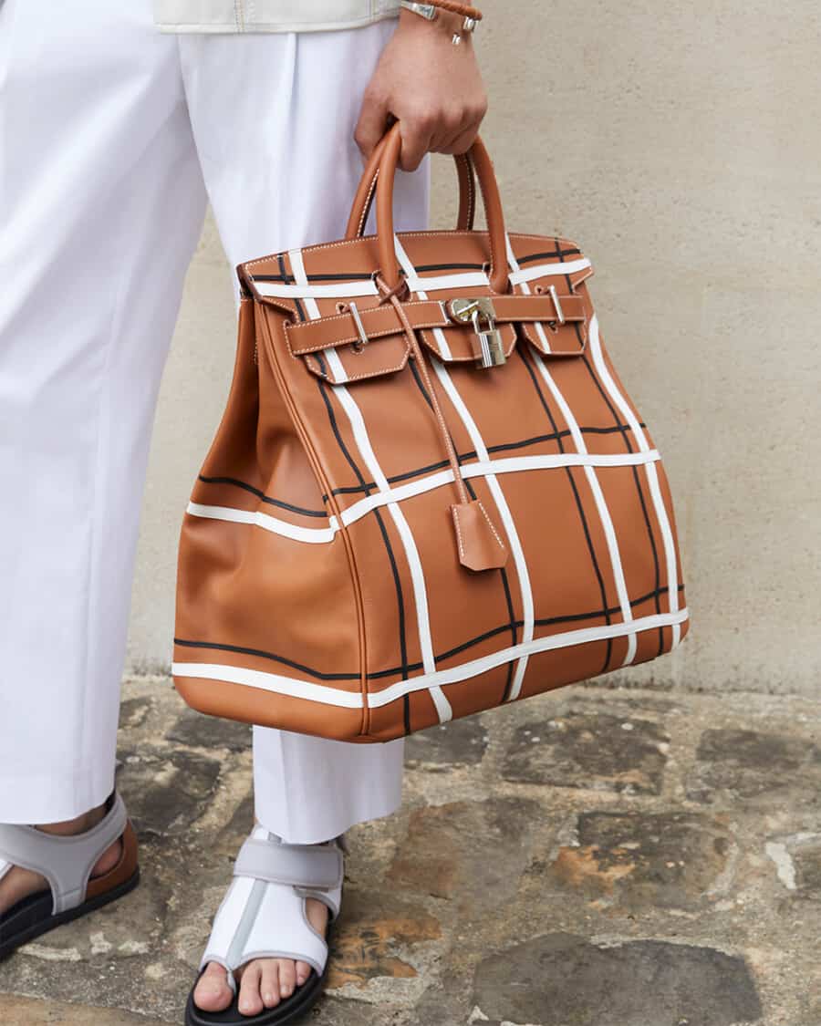Man holding a luxury tan brown leather Hermes tote bag with lock