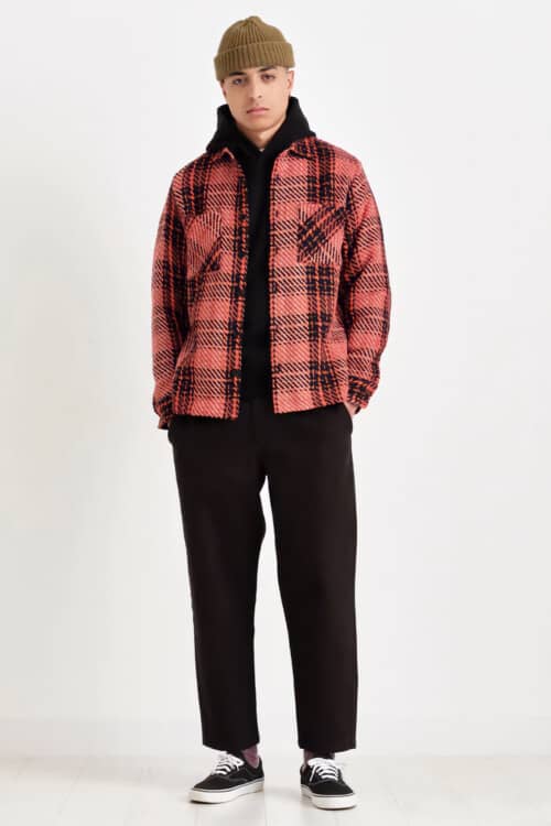 Men's black wide cropped pants, black hoodie, red and black check flannel overshirt, green beanie and black skate shoes outfit