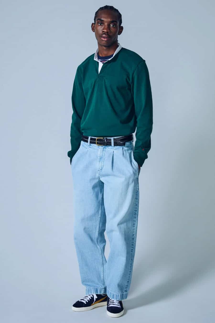 Men's wide light blue pleated jeans, black woven leather belt, marine blue rugby shirt and navy suede sneakers outfit