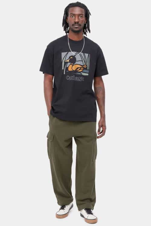 Men's loose green cargo pants, black graphic T-shirt, skate shoes and silver necklace streetwear outfit