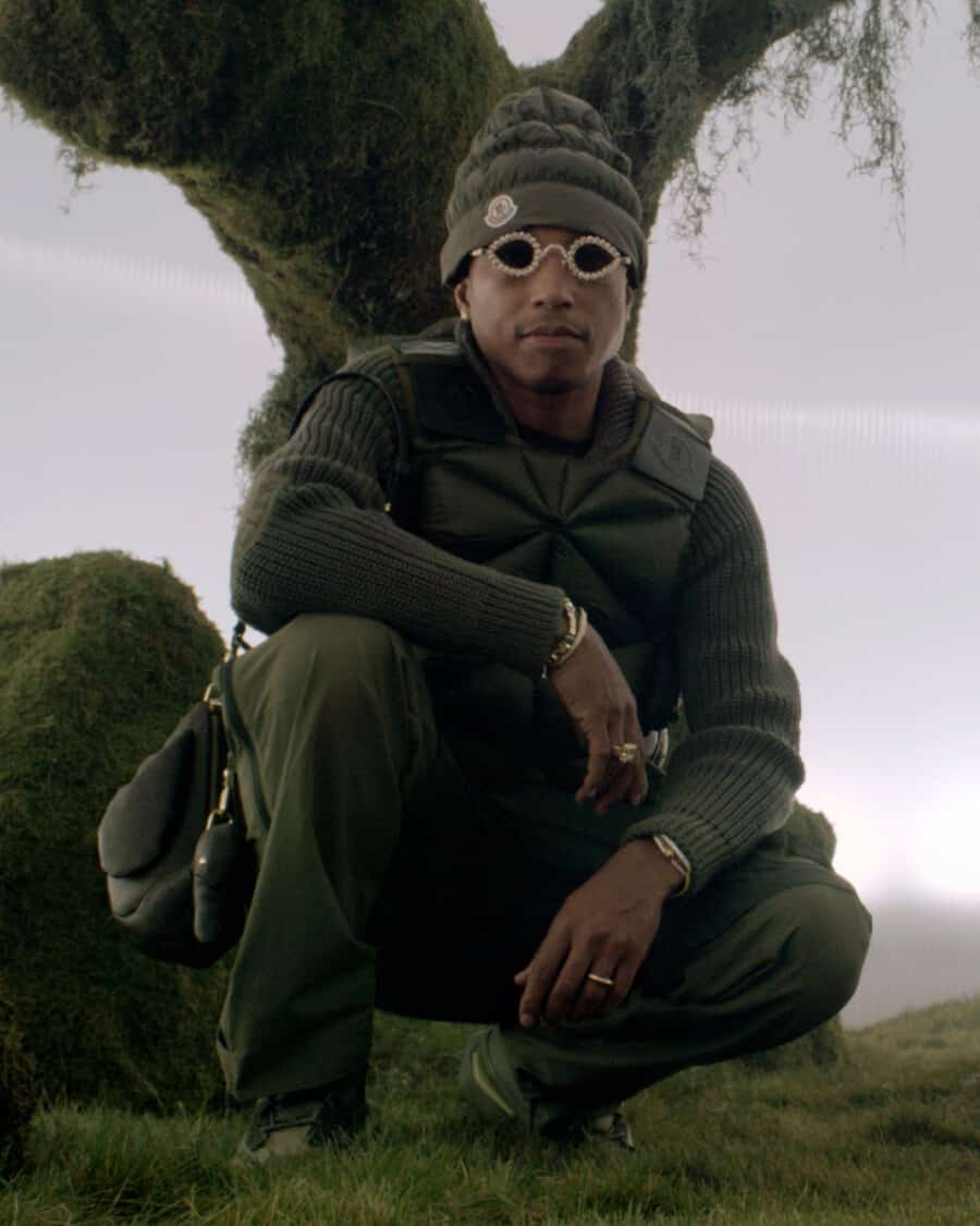 Pharrell Williams wearing green Moncler pants, ribbed sweater, beanie and vest