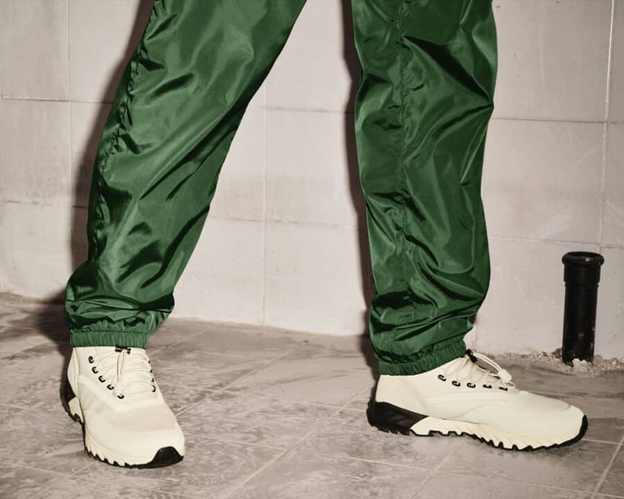 Moncler men's shiny green nylon pants worn with white trail running shoes