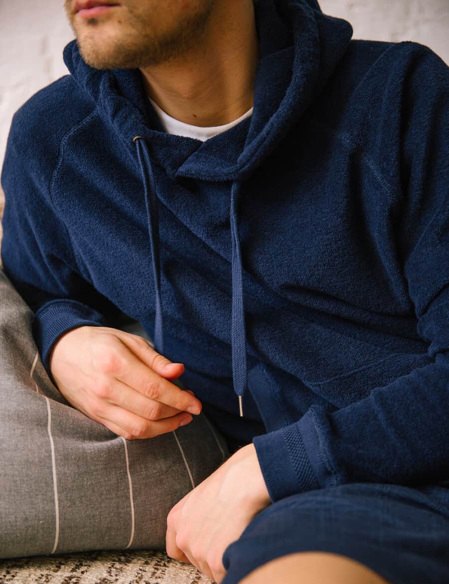 Man wearing a navy blue terry towelling lightweight hoodie over a white T-shirt