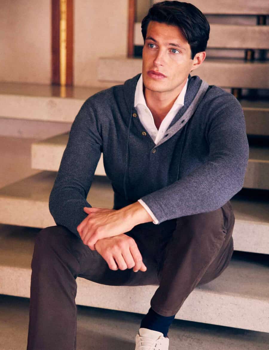 Man wearing lightweight navy cashmere hoodie over a white shirt with brown chino pants