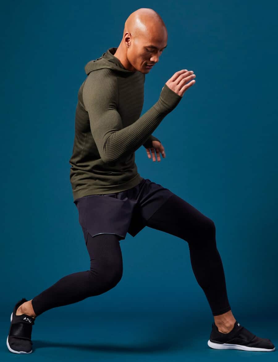 Man wearing lightweight green knitted hoodie with gym shorts, compression leggings and gym sneakers