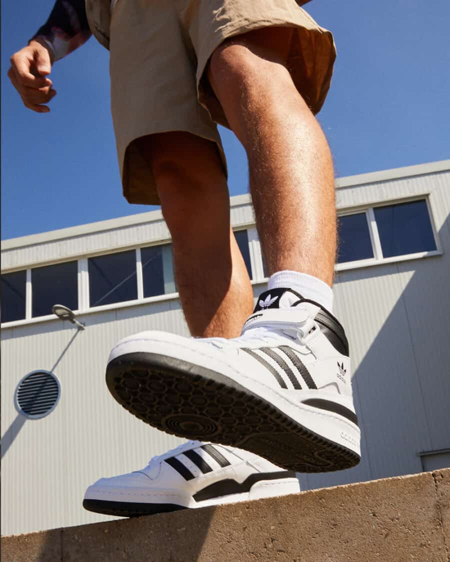Men's Adidas Forum Mid sneaker worn on feet with white socks and khaki shorts