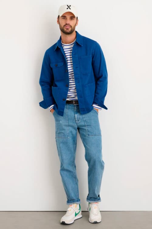 Men's light wash jeans, breton top, blue chore jacket, baseball cap and Nike sneakers outfit