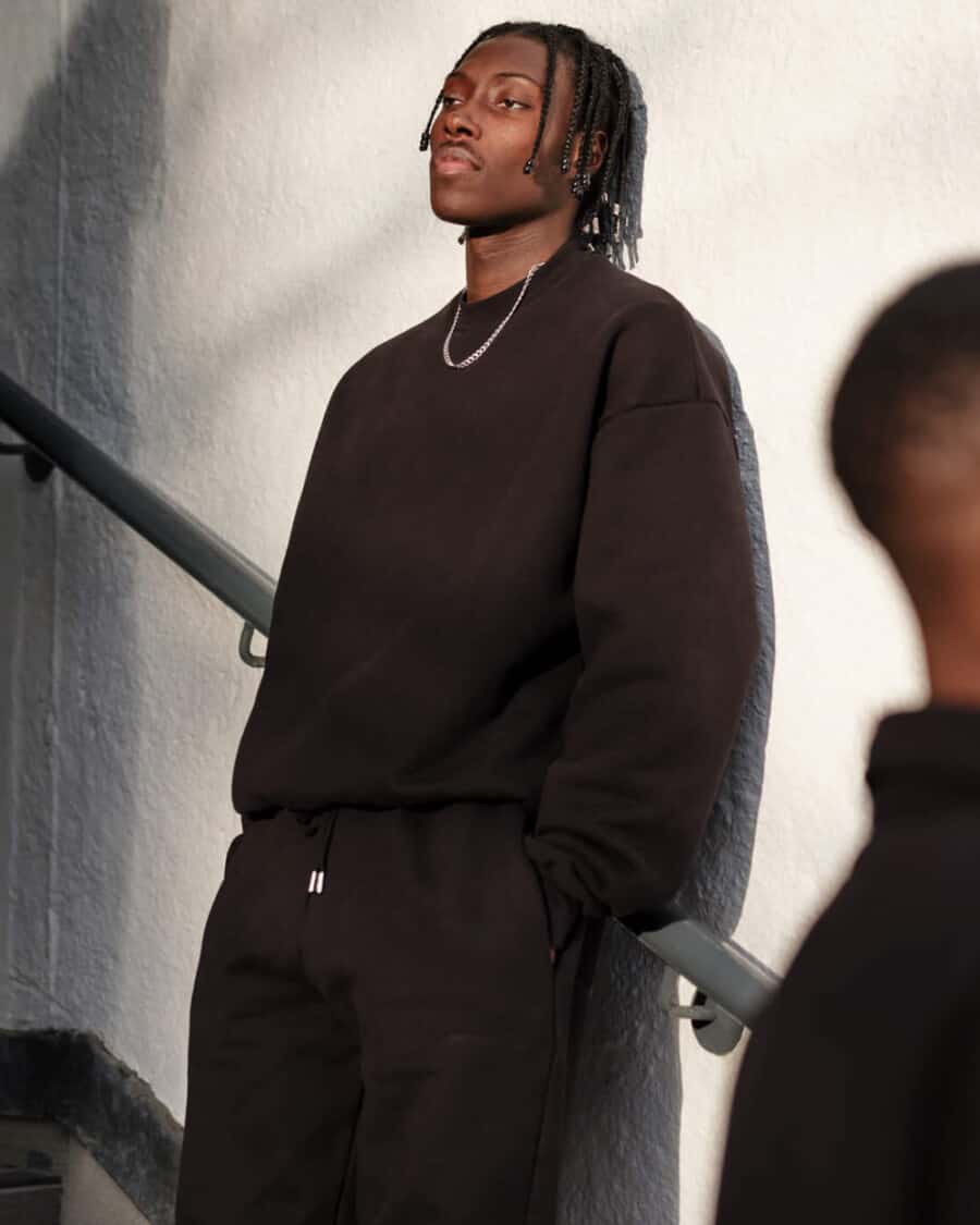 Man wearing matching black heavyweight sweatshirt and sweatpants with a gold chain necklace