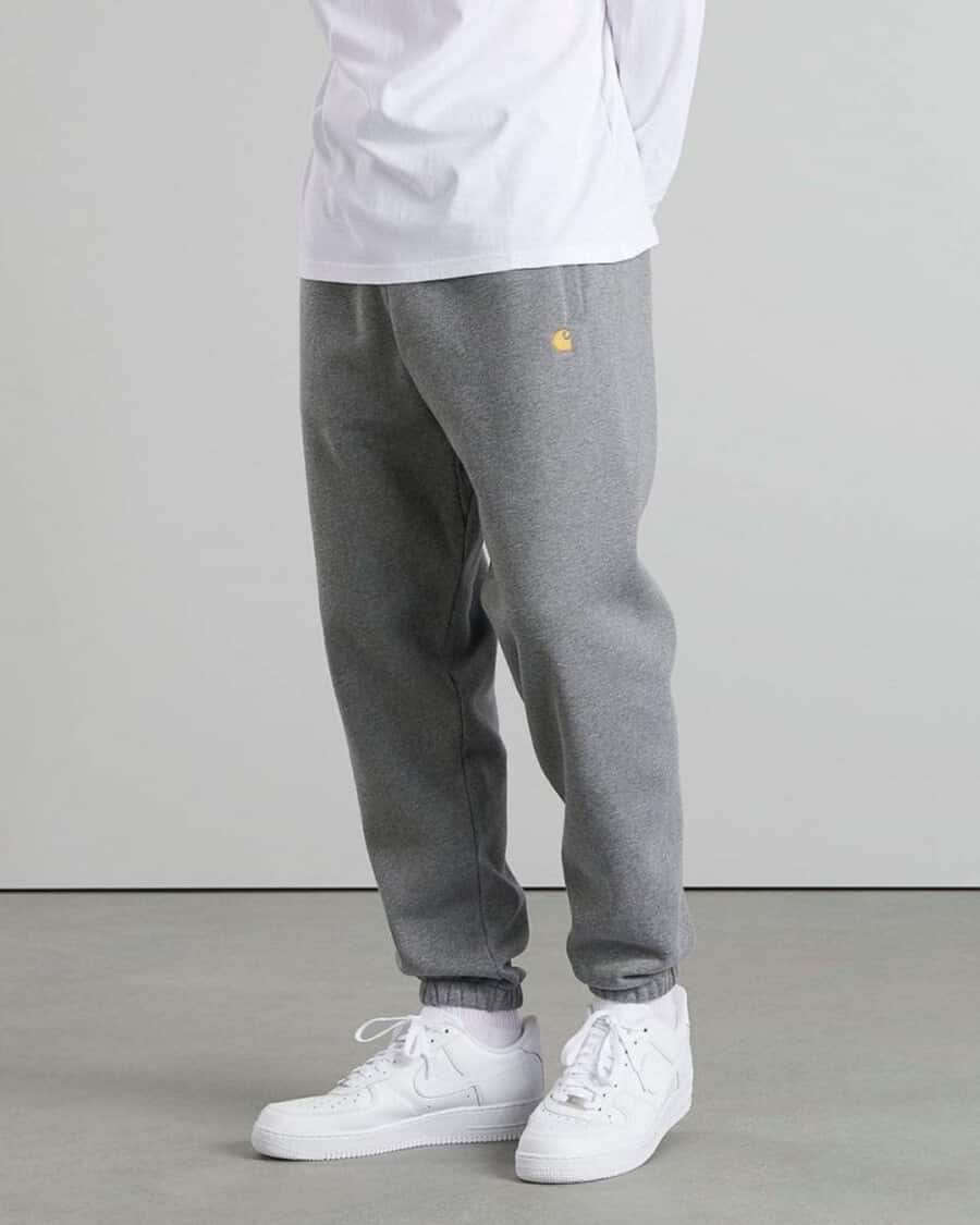 Man wearing grey heavyweight Carhartt WIP sweatpants with white Air Force Ones and white long sleeve T-shirt