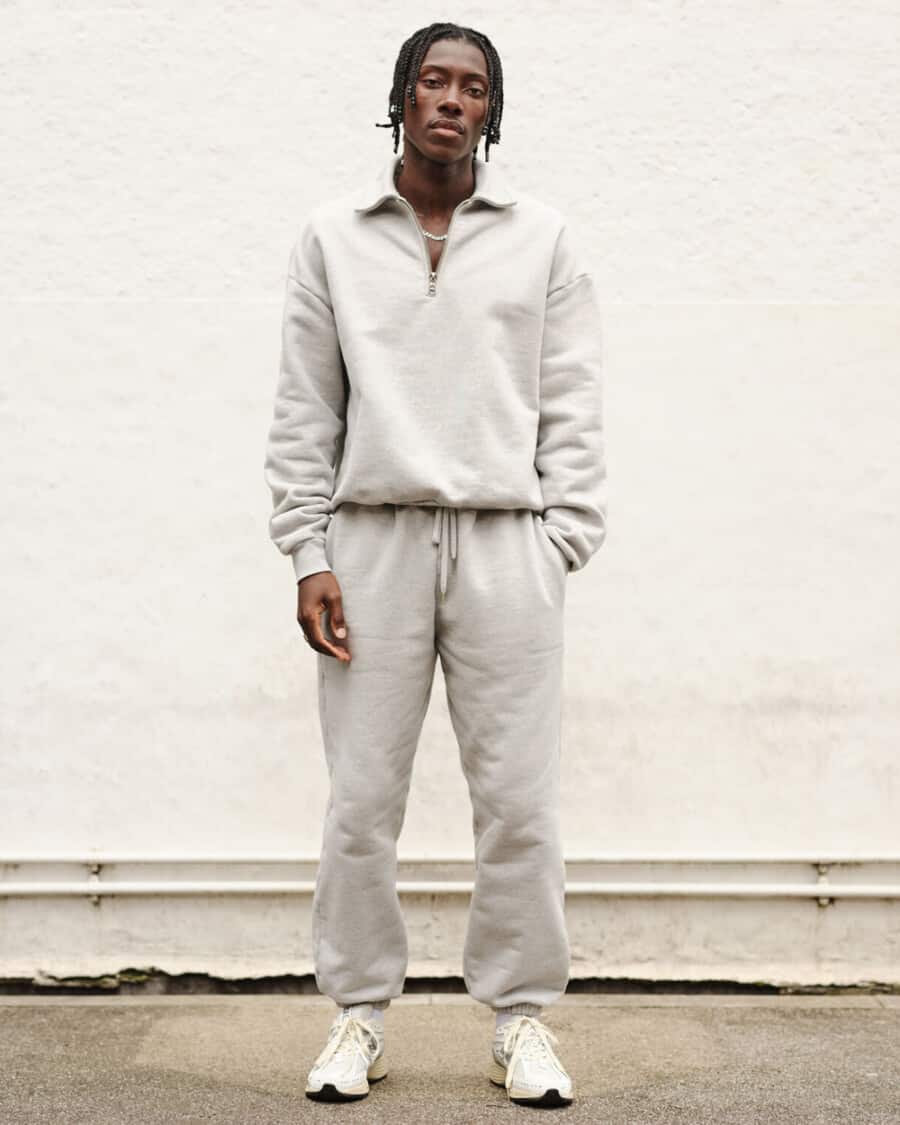 Man wearing a matching heavyweight zip sweatshirt and sweatpants combination in grey with white sneakers