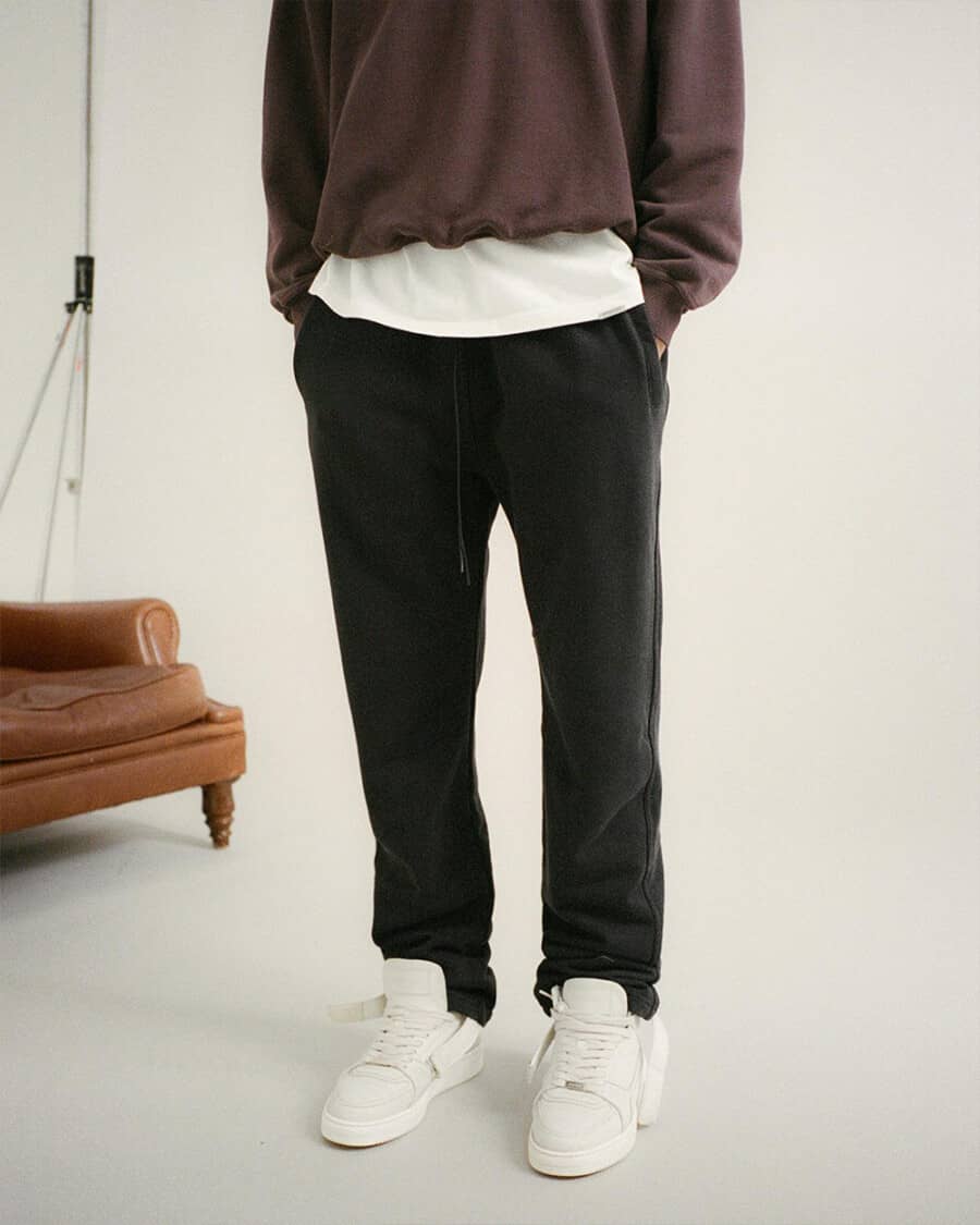 Man wearing heavyweight black sweatpants with a white T-shirt, thick brown sweatshirt and chunky white sneakers