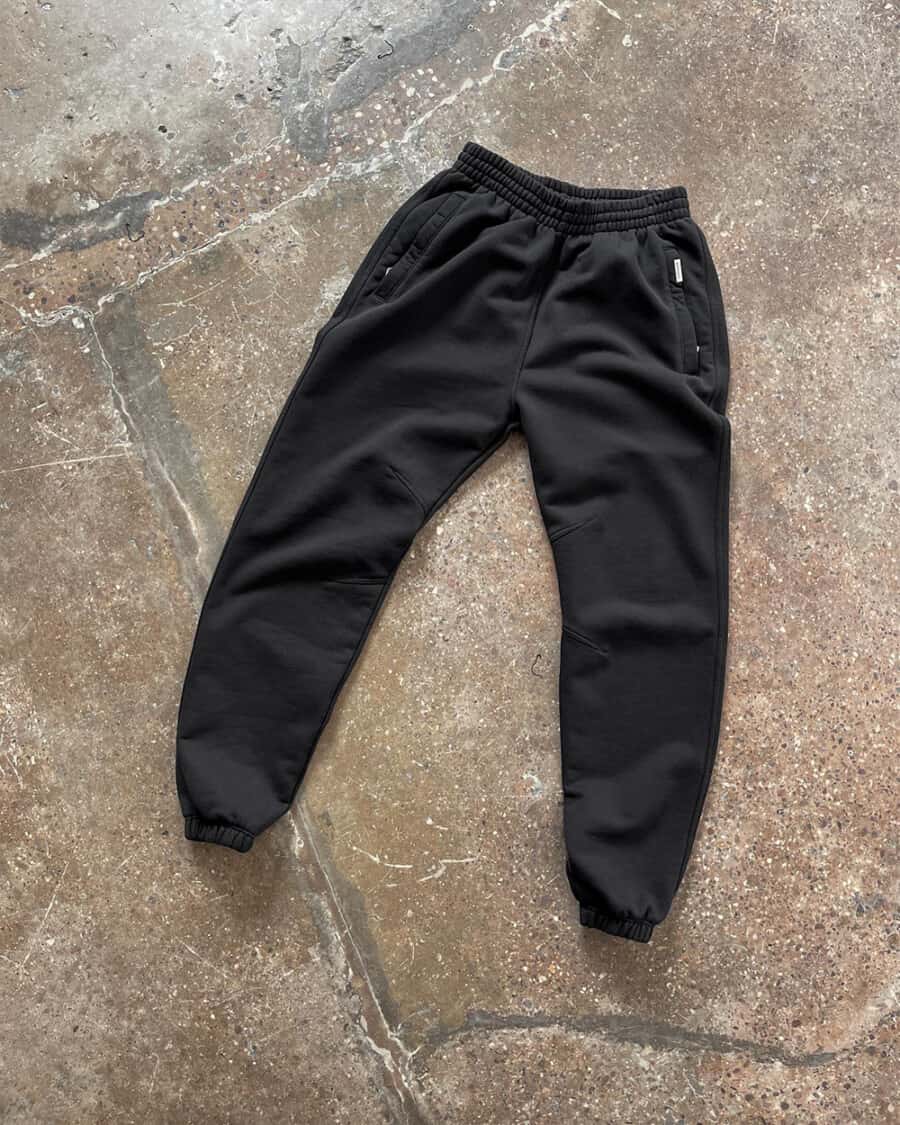 A pair of black heavyweight sweatpants for men laid out on floor by Represent