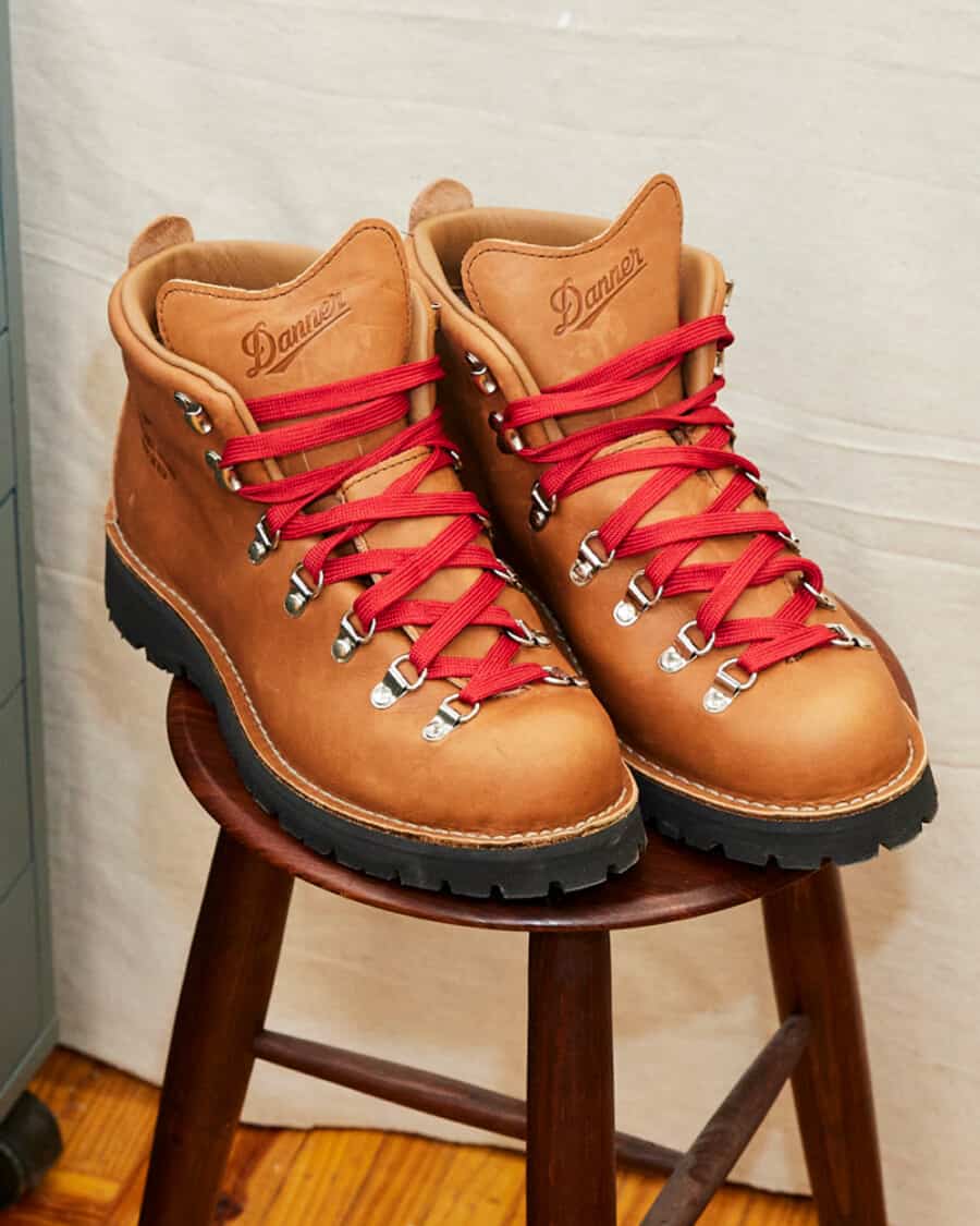 A pair of tan leather Danner hiking work boots on a wooden stool