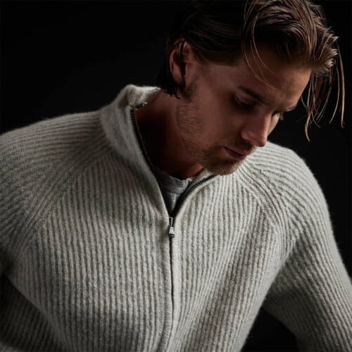 Close up of a man wearing a James Perse ribbed full zip grey cardigan