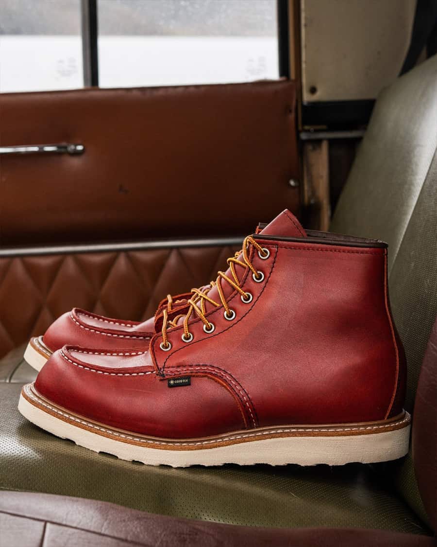 A pair of burgundy leather moc toe work boots by Red Wing on a green leather chair