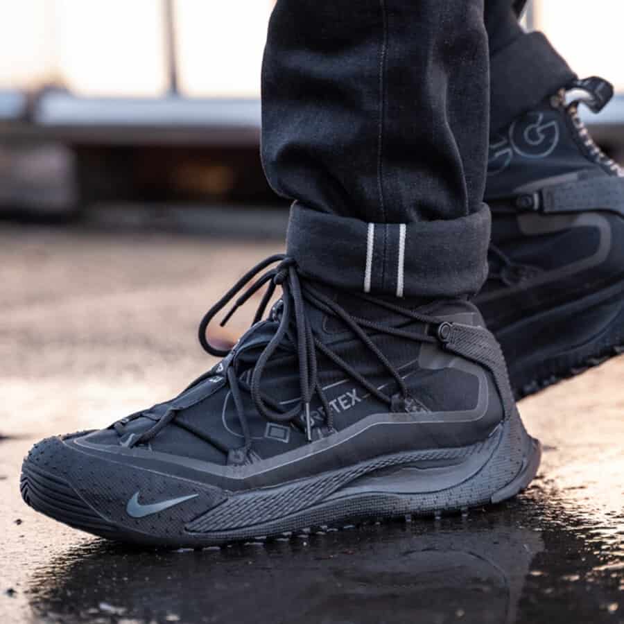 Black Nike ACG boot on feet worn with turned up black jeans