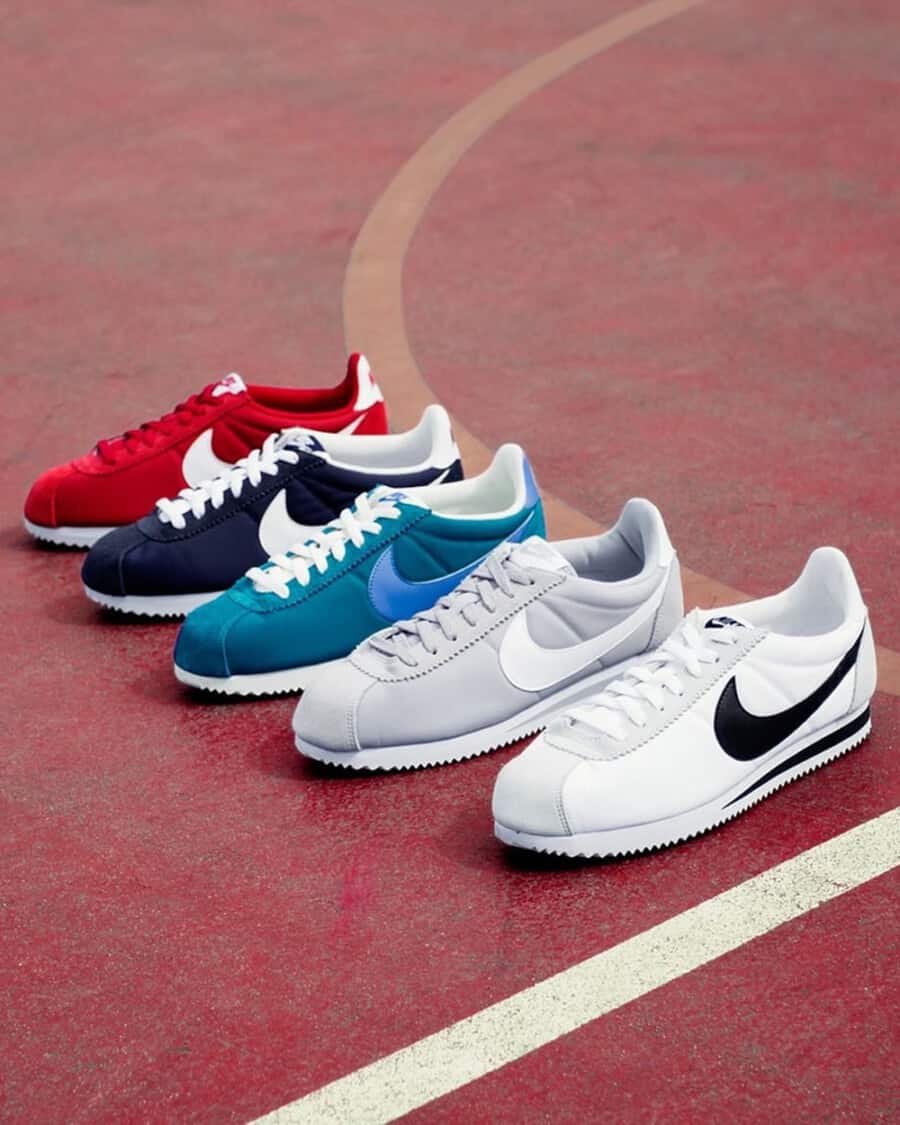 A selection of men's retro Nike Cortez sneakers laid out on a red clay court