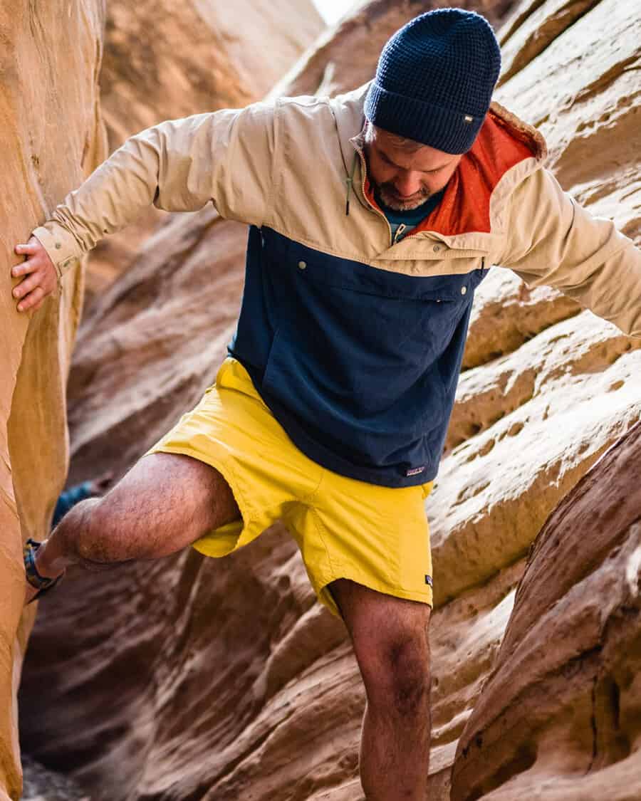 Man rock climbing wearing yellow Patagonia shorts and a blue/khaki overhead anorak