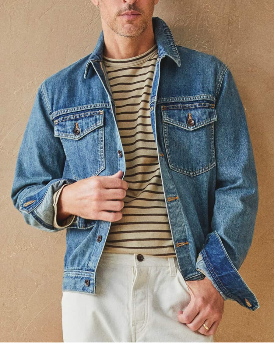 Man wearing mid wash denim jacket, striped T-shirt and white jeans