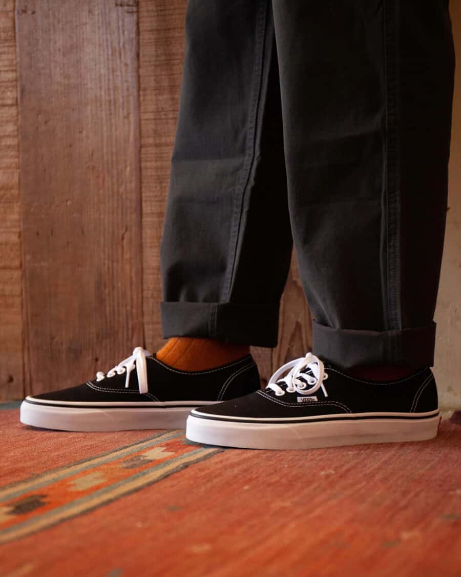 Men's retro black Van Authentic snekaers worn with orange socks and loose black pants