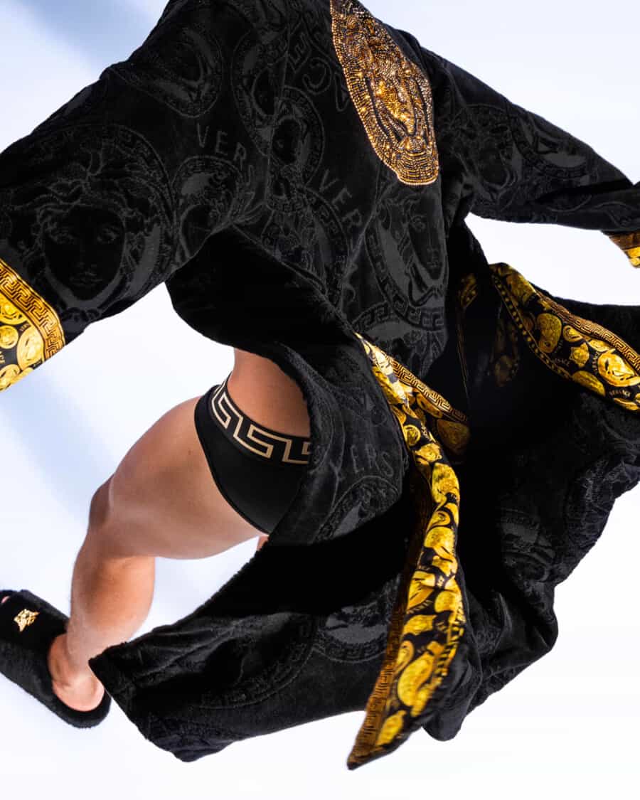 Man wearing Versace black and gold trunks and robe