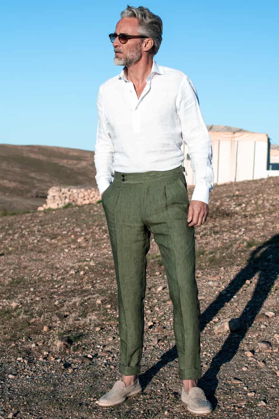 Men's green tailored linen pants with a tucked in white popover shirt and stone suede loafers outfit