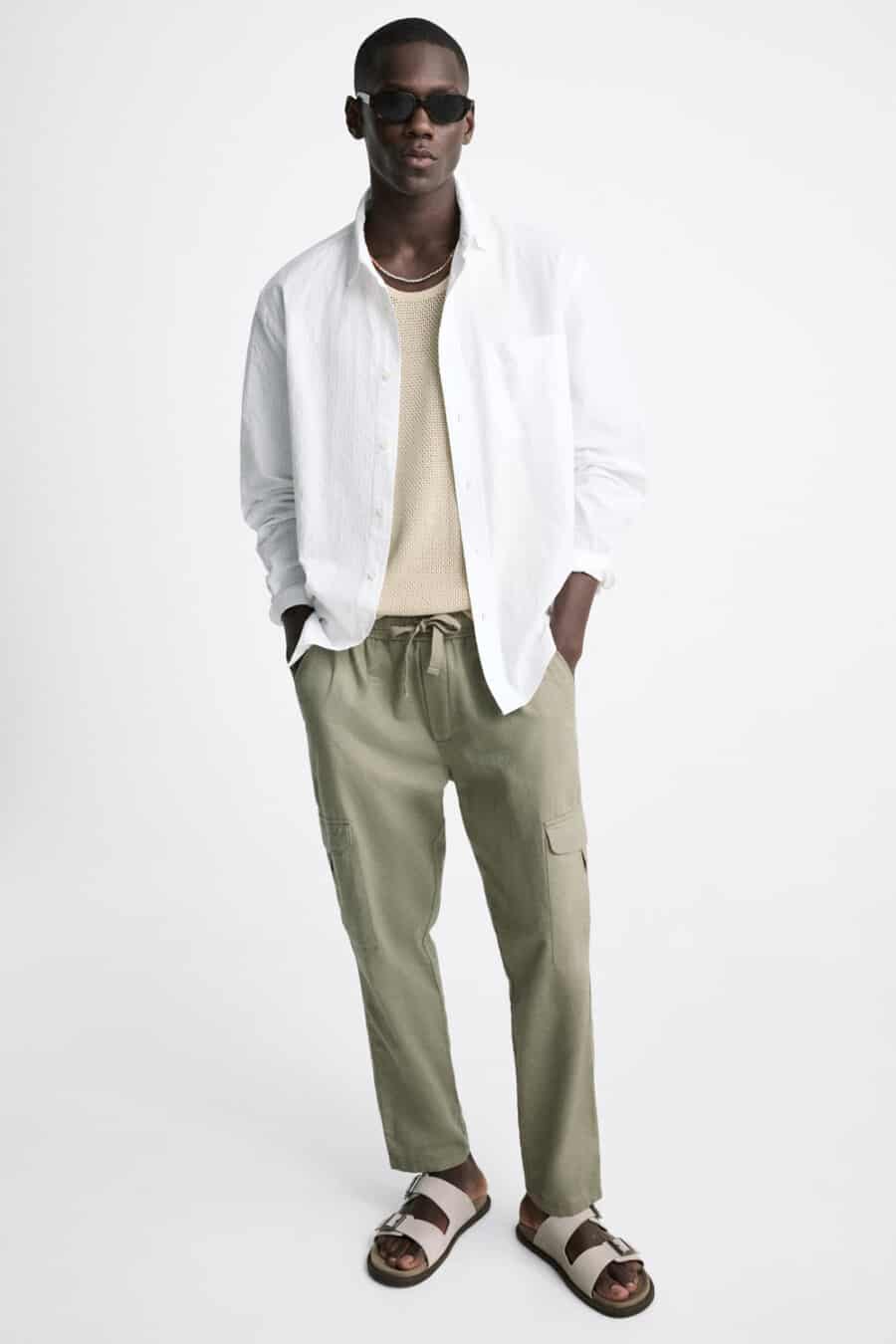 Men's green cargo pants, knit cream T-shirt, open white shirt and stone sandals outfit